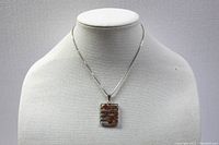 Front view of pendant and chain on neutral display bust showing full necklace length and design