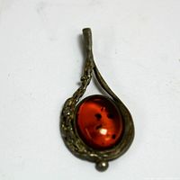 Front view of pendant showing amber cabochon with visible inclusions and silver setting with branch motif