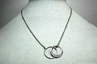 Full view of the sterling silver necklace on display mannequin showing chain length and double ring pendant.