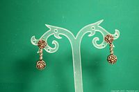 Pair of sterling silver double circle dangle earrings shown on display stand against green backdrop.