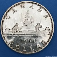Reverse side of the 1960 Canadian silver dollar coin showing a canoe with two Indigenous people, tree, and inscriptions 'CANADA', 'DOLLAR', and year '1960'.