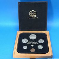 Full view of the 1986 Canadian coin set inside the wooden box with Olympic emblem on lid.