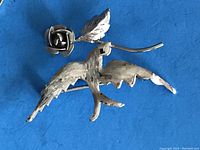 Brooch showing the side with outstretched swallow wings holding the rose and leaf.