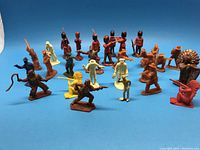 Wide view of group of plastic cowboy, Indian, and British grenadier figures in various colors and poses on blue background