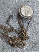 Whole view of Cyclone chain hoist with chains and hook on asphalt surface