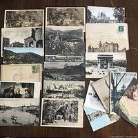 Collection of approximately 20 postcards spread out showing a mixture of black and white landscape and cityscape images, one colored artistic image, with some postmarked and handwritten in Italian.