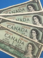 Front side of 4 circulated Canadian 1954 one dollar banknotes showing Queen Elizabeth II portrait and red serial numbers.