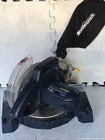 Full view of Mastercraft compound mitre saw with dust bag attached shown on a white surface.