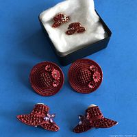 Top view of all three pairs of Red Hat Society earrings on blue background.