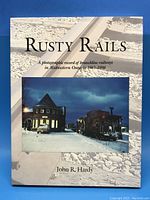 Front cover of the Rusty Rails book showing title, subtitle, photograph of a train beside a historic building, author's name.