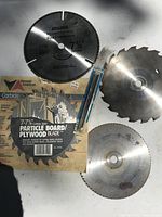 Photo showing multiple circular saw blades including a 7-7/8 inch carbide blade in packaging and several other round blades with teeth.