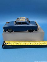 Blue vintage tin friction limousine car toy with roof luggage rack and 'LIMOUSINE' sign. Side view with ruler indicating length approximately 5.5 inches.
