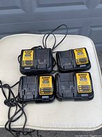 Four DeWalt DCB112 battery chargers 12V/20V Max lithium ion batteries, with visible model number and power cords, placed on a cushioned surface.