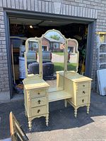 Full frontal photo of the vintage yellow ladies vanity with tri-fold mirror, showing the two pedestal drawer units and turned legs.