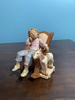 Front and side view of the porcelain figurine showing the boy in a rocking chair and toy horse.