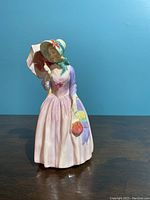 Frontal photo of the figurine showing details of dress, bonnet, face, and parasol.