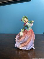 Front view of the Royal Doulton figurine 'Autumn Breezes' depicting a woman in a flowing dress and bonnet.