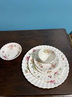 6-piece Royal Doulton Clovelley place setting including cup, saucer, bread plate, salad plate, dinner plate, and bowl displayed stacked on a dark wood surface.