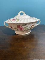 Side view of the Royal Doulton Clovelley covered serving bowl on wood surface against blue background