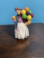 Full view of the Royal Doulton 'Biddy Pennyfarthing' porcelain figurine, showing the elderly woman holding balloons and flowers.