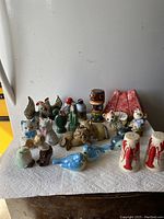 Overview photo of the lot showing all 12 sets of assorted ceramic salt and pepper shakers arranged on a table against a wall.