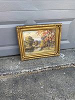 Framed painting leaning against garage door on concrete surface, showing full lot