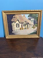 Oil painting on board in ornate gold frame leaning against blue wall