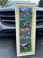 Framed 3D fabric panel wall art with South American village scene, set against car front grille for scale