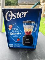 Front view of the Oster blender box showing product image, brand, key features including 5 speeds, ice crushing power, 700 watts, and 4 cup capacity.