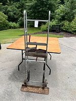 Front view of the tall hand truck dolly showing the full frame, base plate, wheels, and red handles.