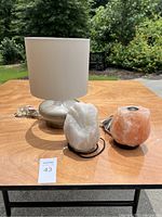 Overall shot of the regular lamp with silver base and white shade, white salt lamp on black stand, and orange salt lamp with wooden base.