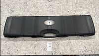 Closed long black hard case with a built-in handle and multiple latches on front.