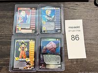 Four Dragon Ball Z trading cards in protective sleeves showing characters Android 18, Android 17, Goku the Proud, and Goku's Touch card.