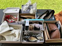 Overview of multiple pairs of women's shoes in their boxes, including boots, heels, and flats in various colors and styles.