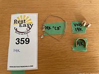 Overview of jewelry lot including chain necklace, hoop earrings, and ring with green labels and penny for scale