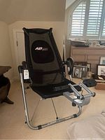 Full front view of the black Tony Little's AB Lounge Xtreme workout machine with mesh backrest and metal frame.