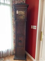 Full view of the tall antique grandfather clock showing wooden case and clock face placement.