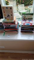 Photo showing two stacks of assorted books including Martha Stewart Living and home decor titles.