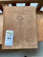 Front cover of large suede-bound book with embossed emblem and lot sticker