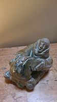 Front view of the carved stone Inuit sculpture seated figure with detailed parka and face.