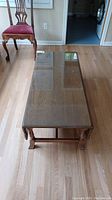 Full view of rectangular solid wood coffee table with glass top showing the overall condition and design.