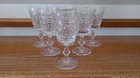 Set of six crystal stemmed glasses arranged in two rows on wooden surface