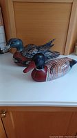 Two wooden duck decoys displayed side by side on a counter