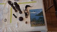 Overview of all wooden African carvings arranged on table next to the hardcover book titled 'Africa A Celebration in Text'