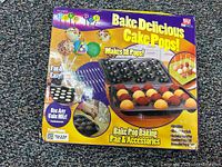 Box packaging of Bake Delicious Cake Pops set showing contents and features, including pan, sticks, cooling tray.