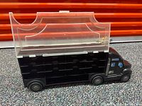 Side view of the black toy car carrier truck showing the clear plastic roof and cab details.