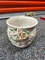 Ornate cream ceramic pot with 3D floral motifs in pastel pink, yellow and green leaves