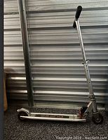 First photo showing a silver kids scooter with adjustable handlebar and black foam grips. The deck is silver with some wear and a rear fender brake is visible.