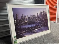 Framed night skyline photograph showing New York City buildings and snowy park with Sprite bottle for size reference.