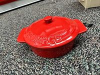 Red ceramic brie baker pot with lid embossed 'FROMAGE' on top.